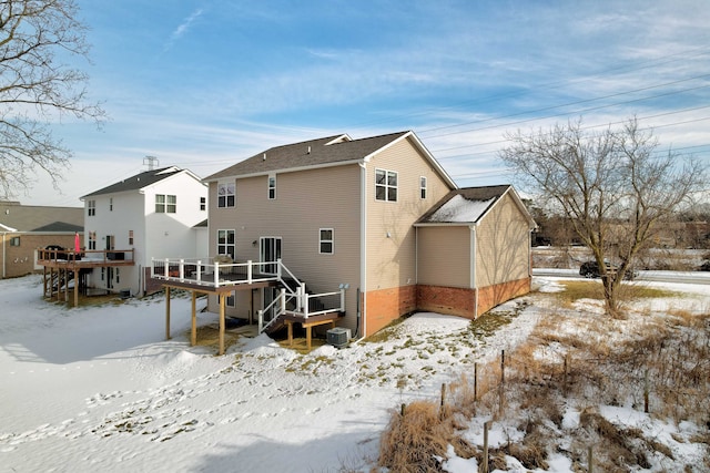 snow covered rear of property featuring a wooden deck and a residential view