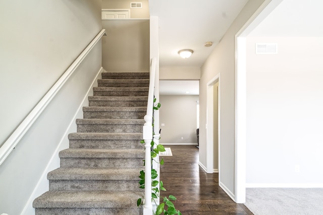 stairway featuring visible vents, baseboards, and wood finished floors