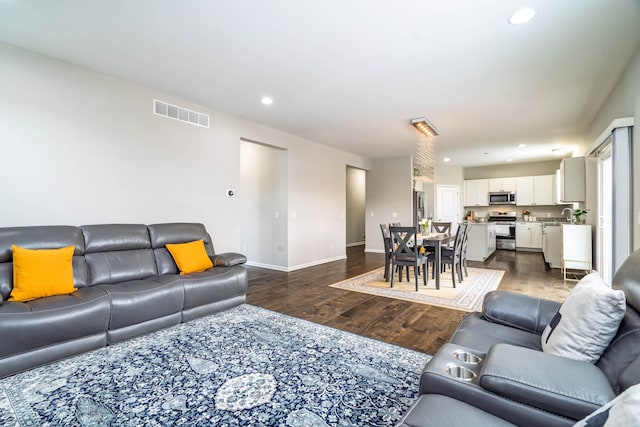 living area with baseboards, visible vents, dark wood-style flooring, and recessed lighting