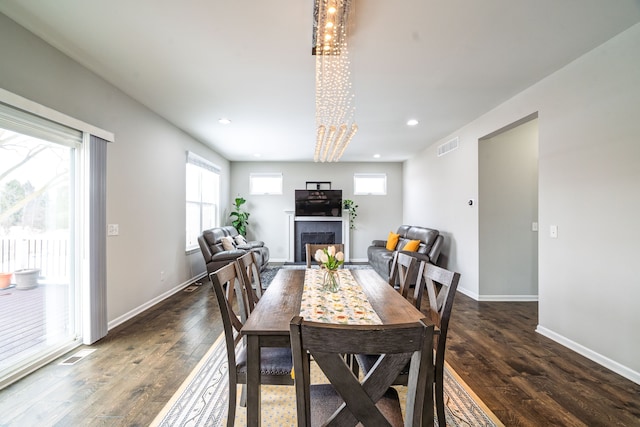 dining room featuring plenty of natural light, a fireplace, and dark wood finished floors