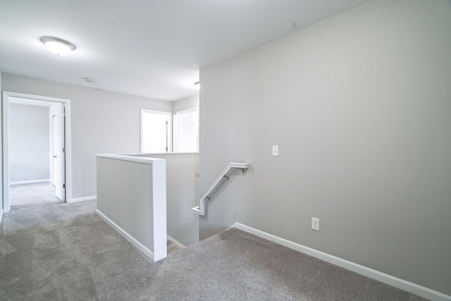 corridor featuring light carpet, baseboards, and an upstairs landing