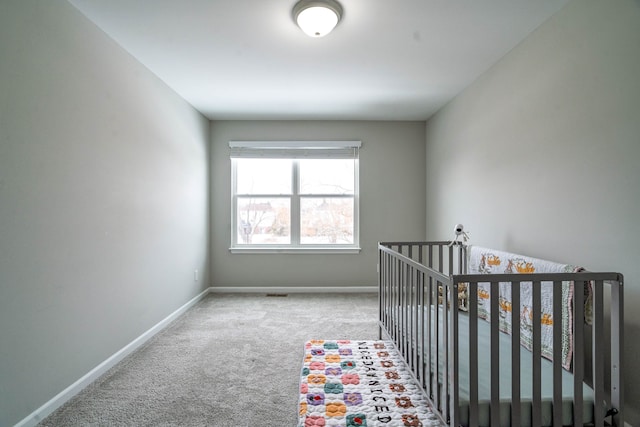 carpeted bedroom with a nursery area, visible vents, and baseboards