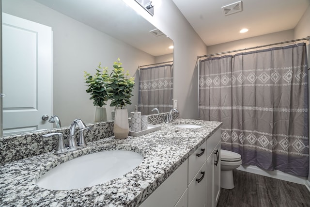 full bathroom with toilet, visible vents, a sink, and wood finished floors