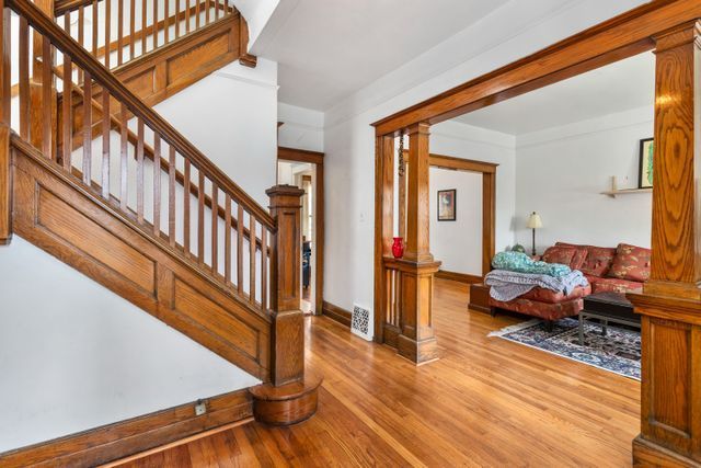 foyer featuring light wood-type flooring, decorative columns, stairway, and baseboards