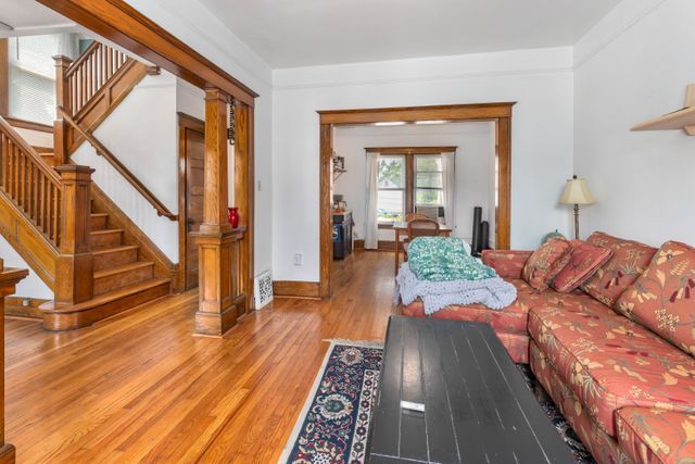 living room with light wood-type flooring, baseboards, and stairs