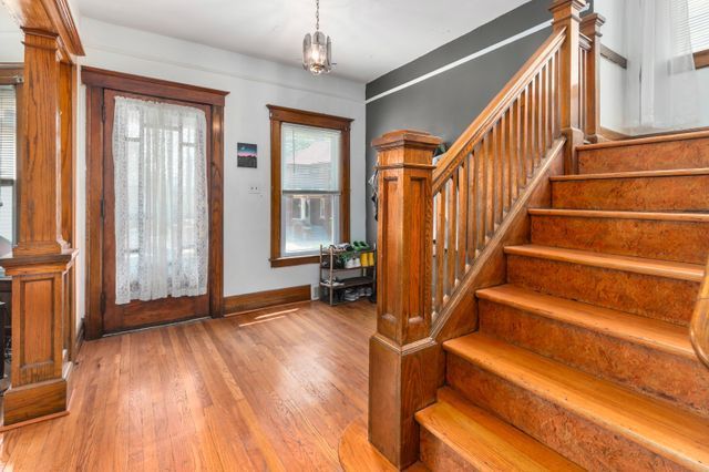 entrance foyer featuring decorative columns, stairway, baseboards, and wood finished floors