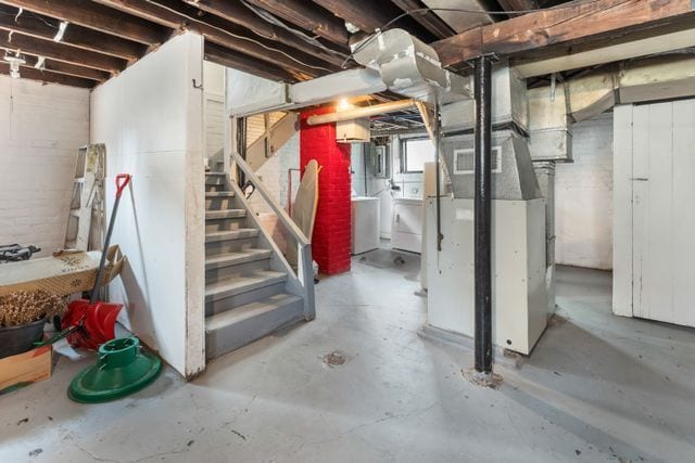 below grade area featuring washing machine and dryer, heating unit, and stairs