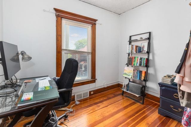 home office featuring wood finished floors, visible vents, and baseboards