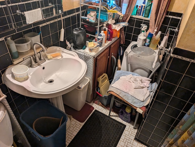 bathroom with a sink, tile patterned flooring, and tile walls