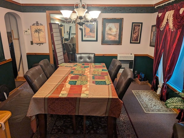 carpeted dining area featuring arched walkways, heating unit, and an inviting chandelier