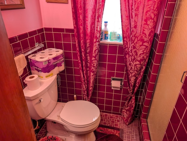 bathroom with toilet, a shower stall, and tile walls