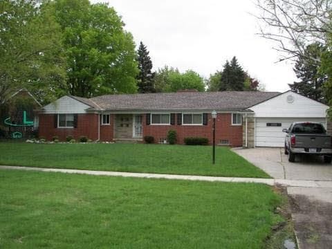 ranch-style house with driveway, an attached garage, and a front yard