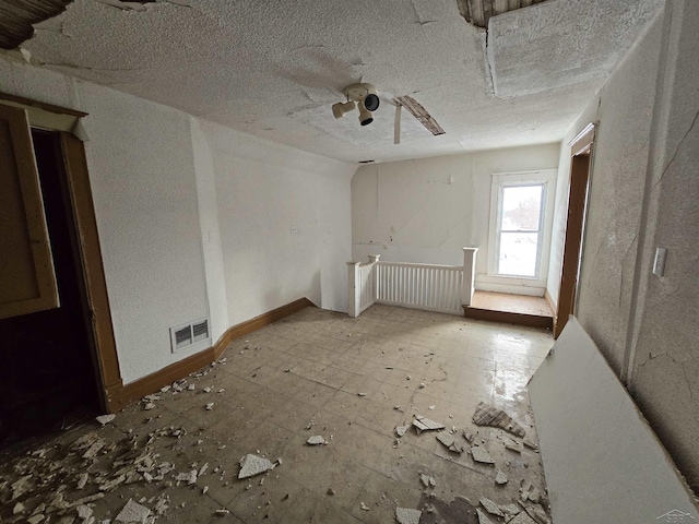 unfurnished room featuring a textured ceiling, visible vents, and a ceiling fan