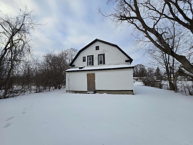 snow covered property featuring a gambrel roof