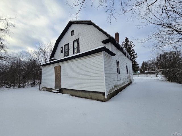 snow covered property with a chimney