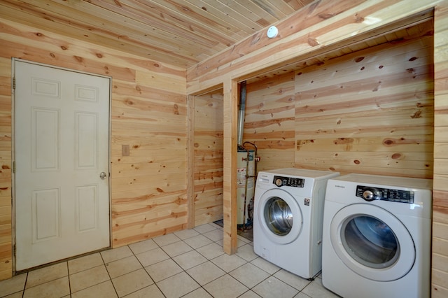 clothes washing area with wood ceiling, wooden walls, washer and clothes dryer, and light tile patterned flooring