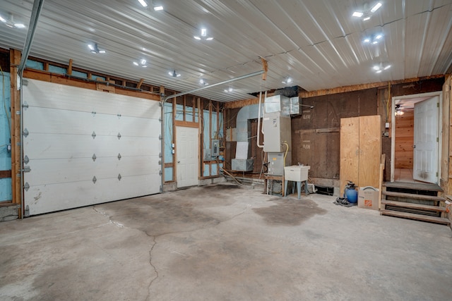 garage featuring a sink, electric panel, and heating unit