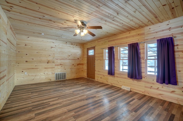 empty room with wooden ceiling, wooden walls, visible vents, and wood finished floors