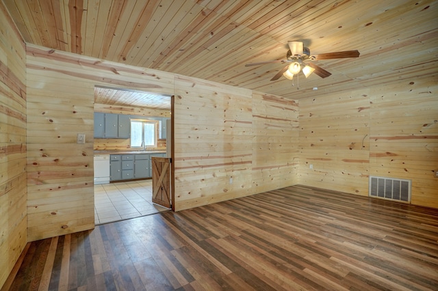 empty room with wood ceiling, visible vents, wood walls, and light wood-style flooring