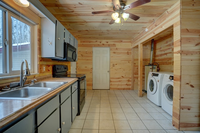 kitchen with washer and clothes dryer, light tile patterned floors, wood ceiling, a sink, and black appliances