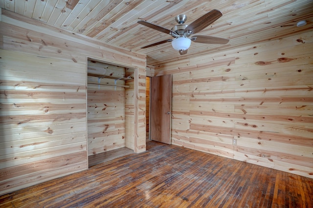 empty room with wooden ceiling, wood walls, a ceiling fan, and dark wood-type flooring