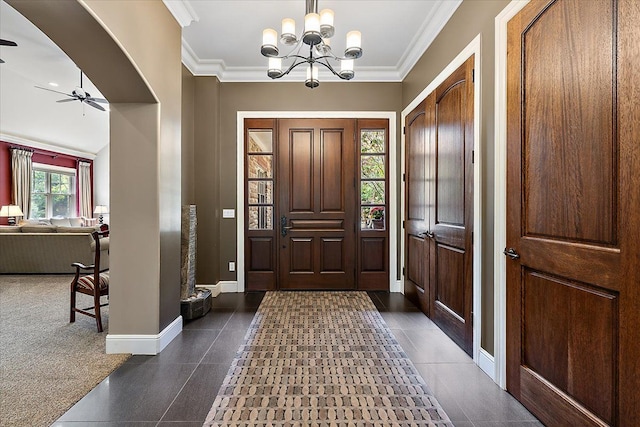 entrance foyer with baseboards, arched walkways, crown molding, and ceiling fan with notable chandelier