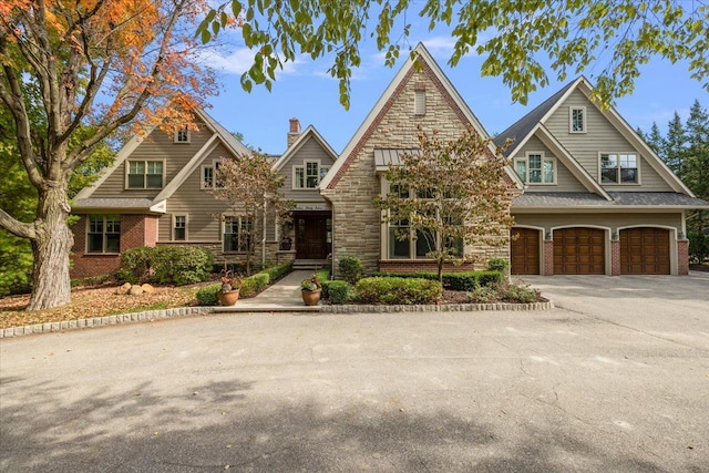 view of front facade featuring a garage, stone siding, brick siding, and driveway