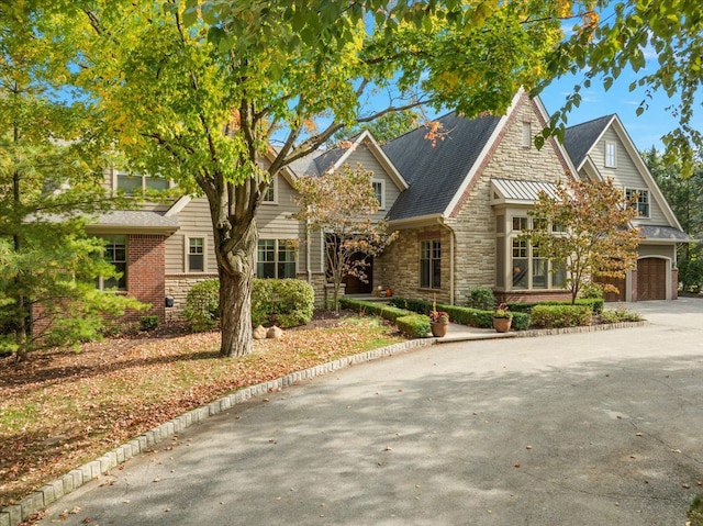 view of front of property featuring a garage, stone siding, and driveway