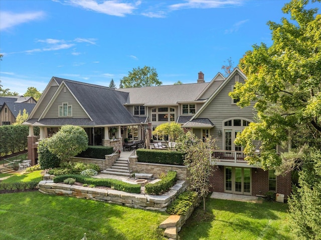 rear view of property with a patio area, a chimney, a lawn, and french doors