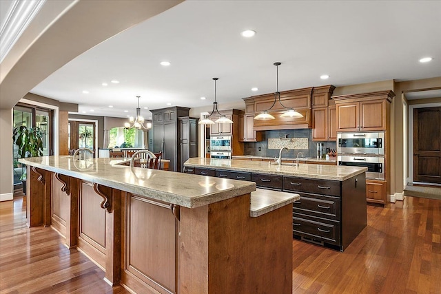 kitchen with brown cabinets, a large island, pendant lighting, and a sink