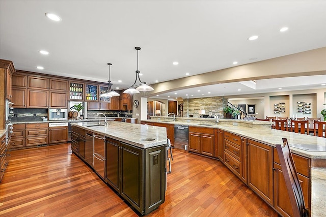 kitchen with dark wood-type flooring, tasteful backsplash, pendant lighting, and a large island with sink