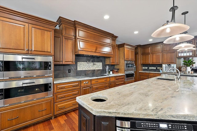 kitchen featuring hanging light fixtures, light stone counters, and a sink