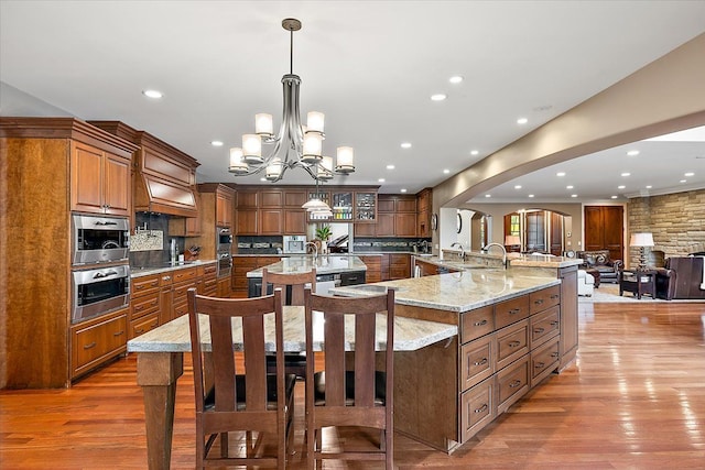 kitchen with open floor plan, a large island, brown cabinetry, and decorative light fixtures