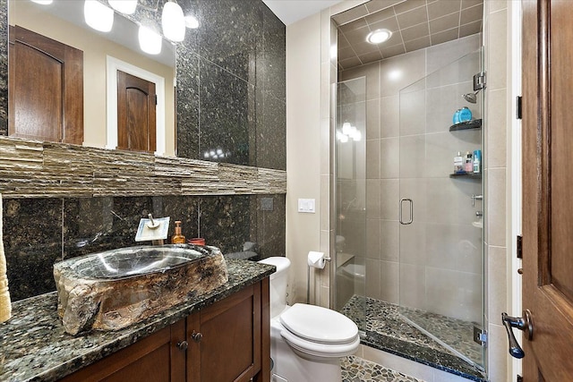 bathroom featuring tile walls, backsplash, toilet, a shower stall, and vanity