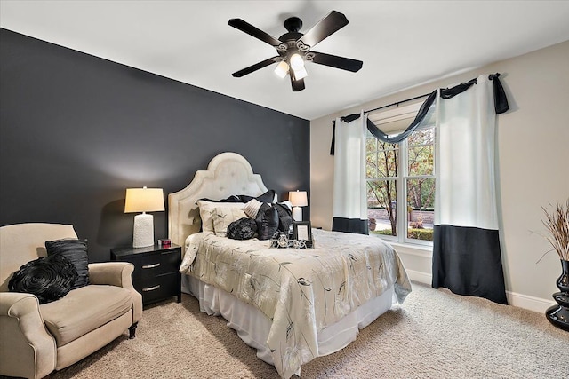 bedroom featuring an accent wall, light carpet, ceiling fan, and baseboards