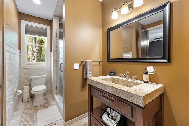 bathroom with tile walls, toilet, a stall shower, vanity, and tile patterned flooring