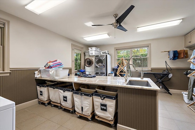 kitchen featuring light stone counters, wainscoting, a sink, and wood walls