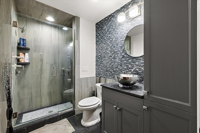 bathroom with a stall shower, vanity, tile walls, and tile patterned floors