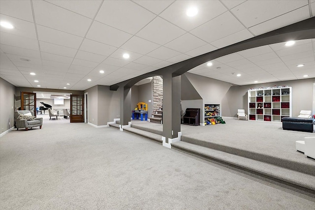 recreation room featuring carpet, arched walkways, and baseboards