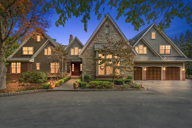 view of front of property featuring a garage, stone siding, and driveway