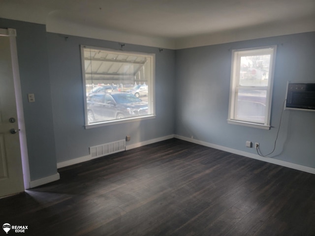 interior space with dark wood-type flooring, visible vents, baseboards, and a wall mounted AC