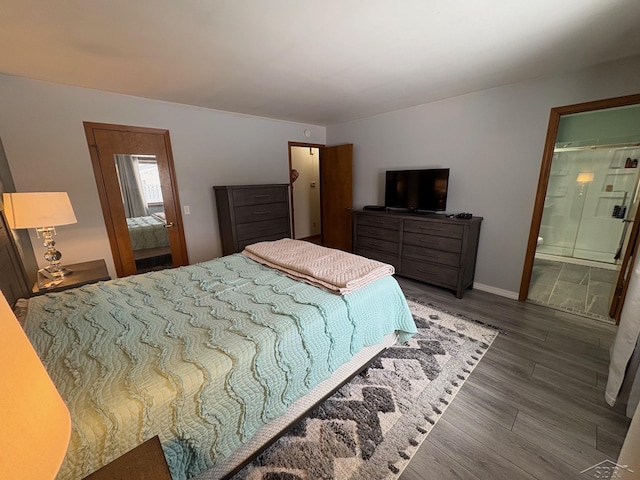 bedroom with connected bathroom, baseboards, and dark wood-type flooring