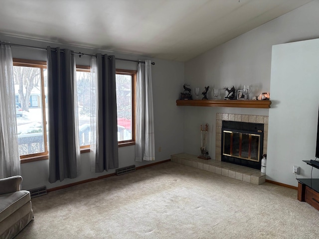 carpeted living room with a tile fireplace, visible vents, vaulted ceiling, and baseboards