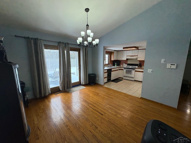 kitchen featuring light wood finished floors, white gas range oven, vaulted ceiling, light countertops, and under cabinet range hood