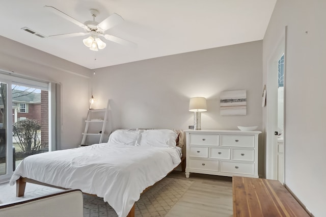 bedroom featuring access to outside, wood finished floors, visible vents, and a ceiling fan