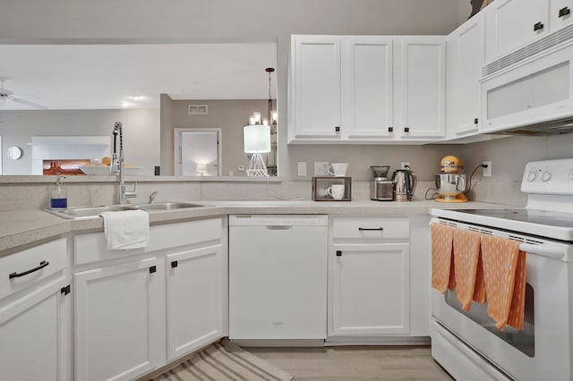 kitchen with light countertops, visible vents, white cabinets, a sink, and white appliances