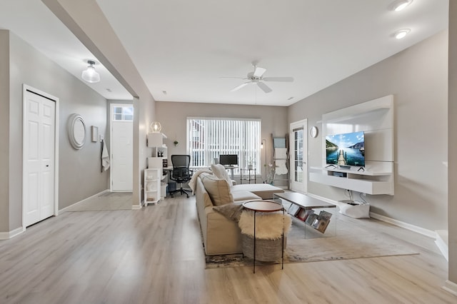 living area with wood finished floors, a ceiling fan, and baseboards