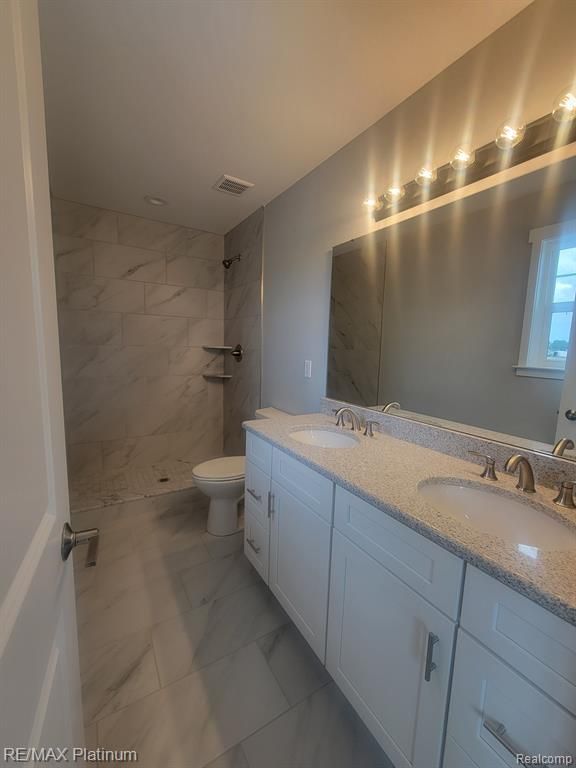 bathroom featuring marble finish floor, double vanity, a sink, and visible vents