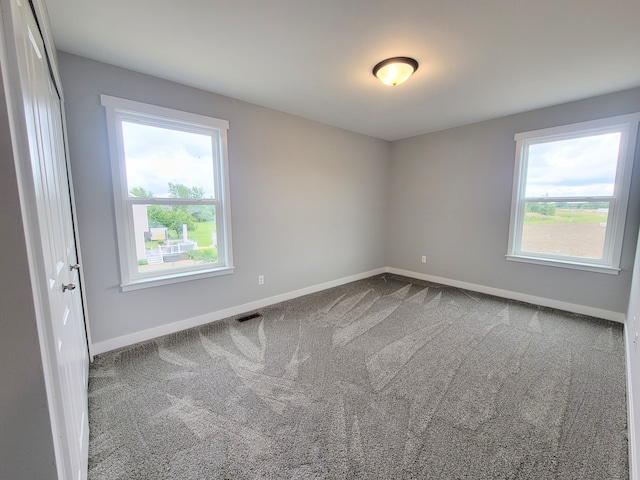 unfurnished room featuring carpet floors, visible vents, and baseboards