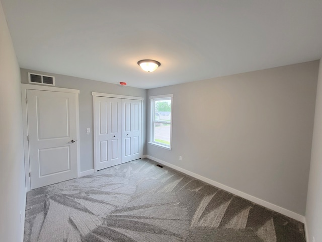 carpeted bedroom featuring baseboards, visible vents, and a closet